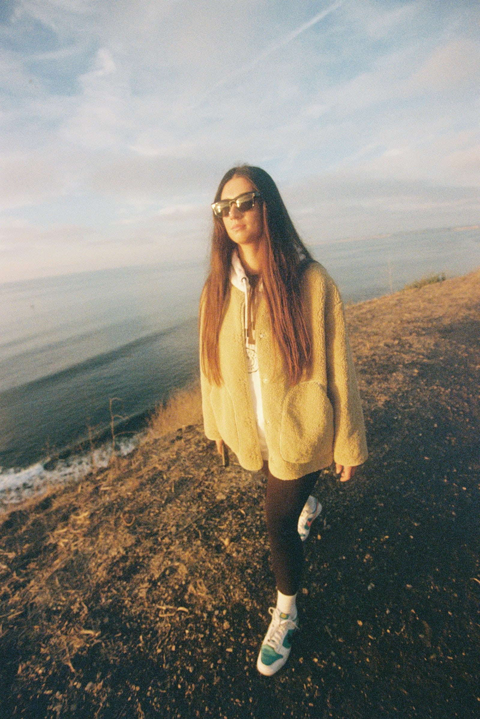 A young traveller walking along the California coast at golden hour